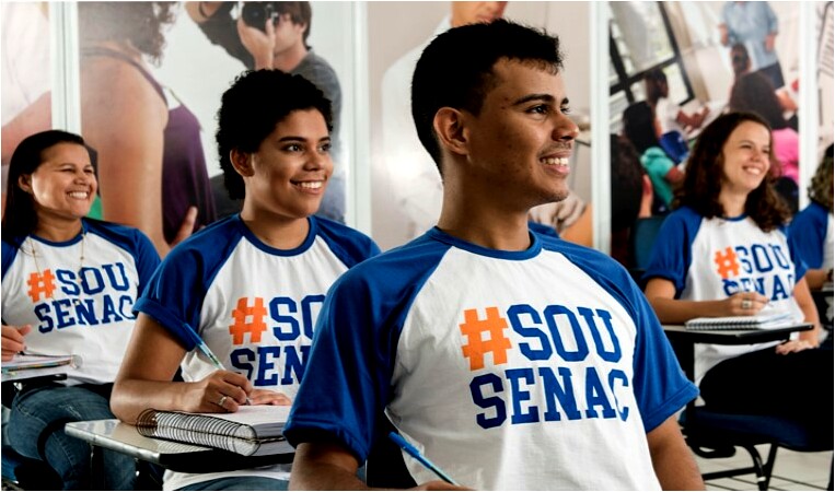 Técnico de enfermagem. Alunos do SENAC sorrindo em sala de aula, usando camisetas com a frase #SouSENAC, participando de curso técnico ou profissionalizante.