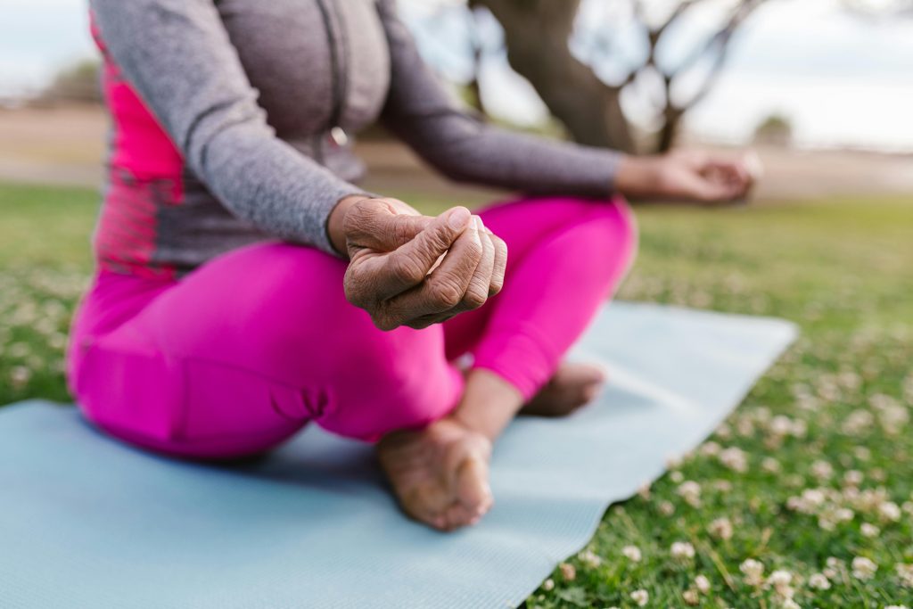 Mulher praticando meditação ao ar livre, técnica eficaz para reduzir o estresse e os sintomas da menopausa.