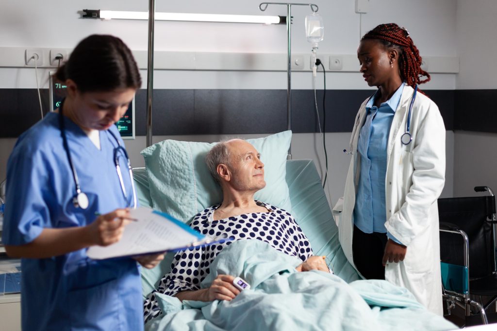 Médicos cuidando de um idoso no hospital, evidenciando os desafios do envelhecimento e as modificações no corpo e saúde.