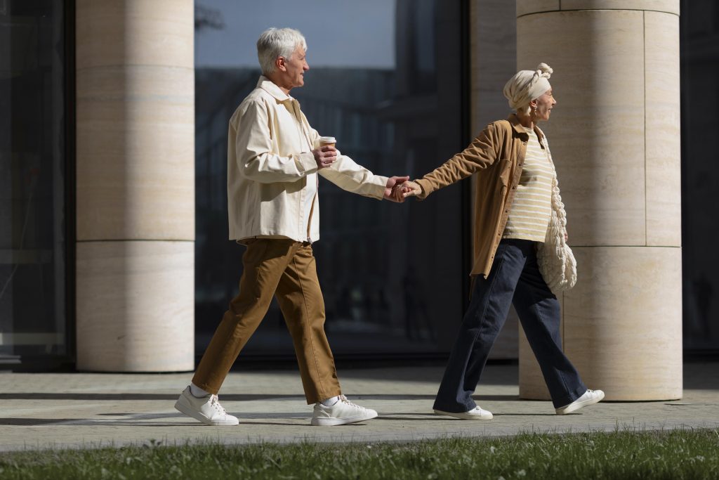 Casal de idosos caminhando de mãos dadas, simbolizando mobilidade segura, autonomia e prevenção de quedas na velhice.