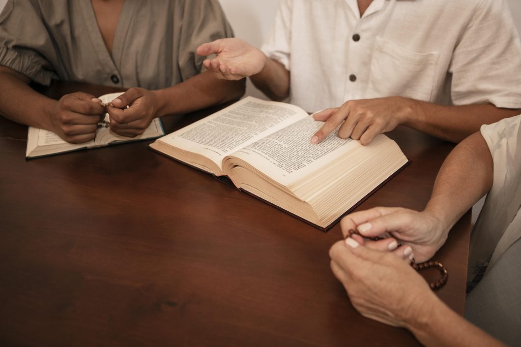 Grupo de pessoas em oração com Bíblia aberta e terço nas mãos, simbolizando fé, espiritualidade e fortalecimento emocional.