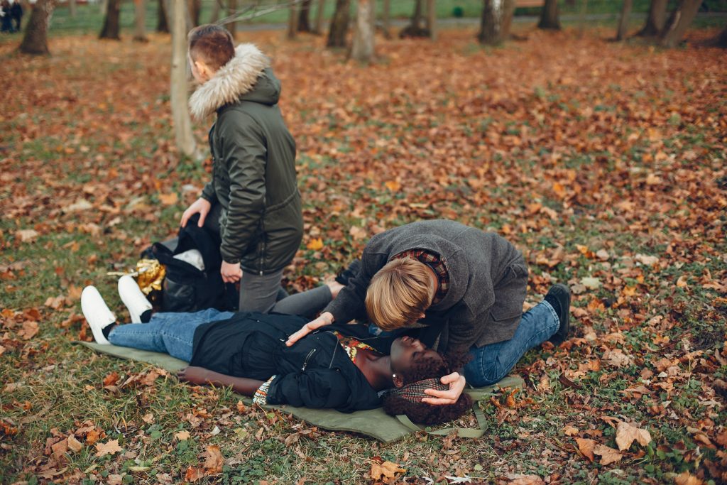 Pessoa recebendo ajuda após uma crise em área externa, ilustrando sinais e sintomas comuns da epilepsia.