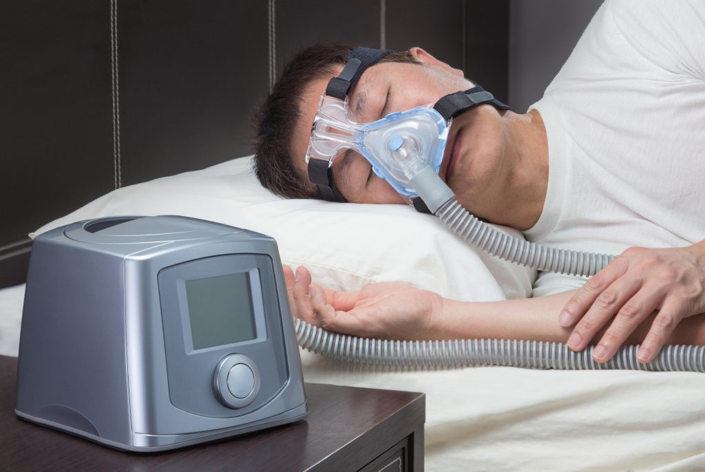 Homem usando máscara CPAP durante o sono para tratar apneia e reduzir riscos à saúde