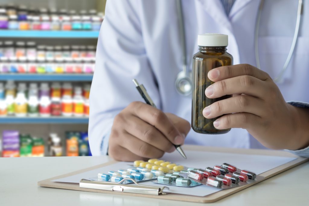 Profissional de saúde analisa frasco de medicamento e cápsulas para estudo de farmacologia.