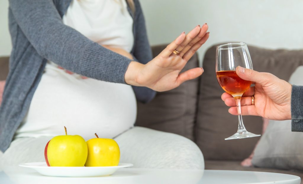 Gestante recusa taça de vinho, reforçando que álcool na gravidez representa risco ao bebê